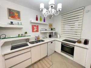 埃拉特Residence du golf的厨房配有白色橱柜、水槽和吊灯。