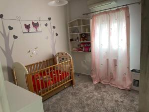 凯法洛斯EVA'S HOME的一间婴儿房,配有一张婴儿床和一幅树壁画