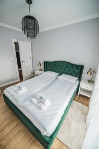 库多瓦-兹德鲁伊Słone Residence Apartamenty & Beer SPA的一间卧室配有一张带白色床单和绿色床头板的床。