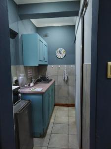 格罗布勒斯达尔Ebenezer Self Catering的厨房配有蓝色橱柜,铺有瓷砖地板。
