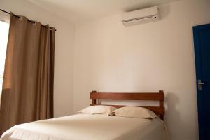大普拉亚Solar Vila Mirim的一间卧室配有一张带白色床单的床和一扇窗户。