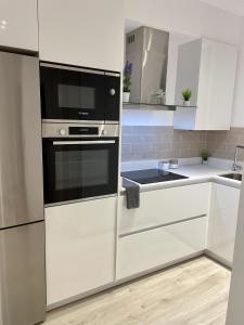 毕尔巴鄂Bilbao Azkuna Home Centro EBI01832的厨房配有白色橱柜和黑微波炉