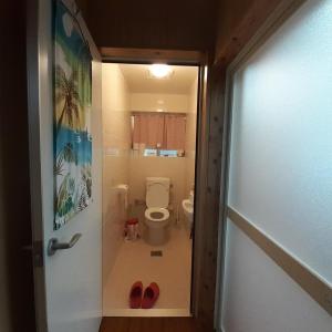 Janadō民泊まったりん人的浴室位于门口,配有卫生间和红色鞋子。
