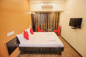 罗纳瓦拉Hotel Sai Niwas的客房配有带红色枕头的床和电视。