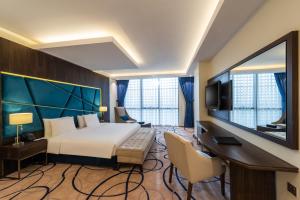 利雅德Warwick Riyadh Al Wezarat的酒店客房设有一张床、一张书桌和一台电视机。