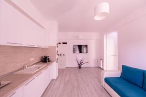 北马马亚-讷沃达里ApartHotel SeaVibes Mamaia Nord的一间白色的厨房,在房间内配有蓝色的沙发