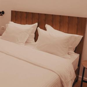 地拉那Hotel Theatro- City Center的白色的床、白色枕头和木制床头板