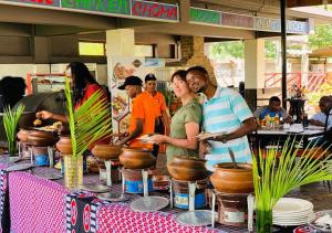 莫希Panone Hotels - King'ori Kilimanjaro Airport的一群人站在桌子旁吃着食物