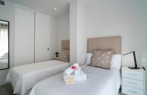 马拉加AAC Málaga - Apartamento luminoso y nuevo, a 1,3km del centro de Málaga的卧室里设有两张带毛巾的床和一只宠物