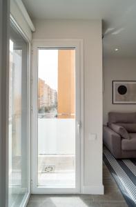马拉加AAC Málaga - Apartamento luminoso y nuevo, a 1,3km del centro de Málaga的滑动玻璃门通向带沙发的客厅