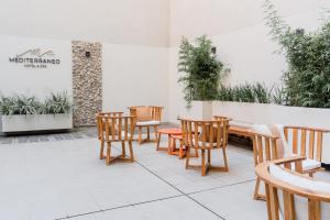 罗萨里奥Mediterráneo Hotel y Spa的庭院设有木椅、桌子和植物