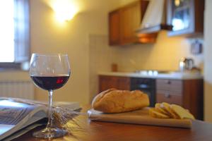 皮恩扎博内罗农庄旅馆的桌上的一杯葡萄酒和一面包