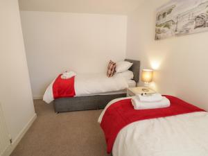 本莱赫Benllech Coastal Retreat的一间卧室配有两张床和一张带台灯的桌子