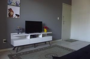 马塞约Braga Apartamento Temporada Maceió的客厅配有白色橱柜上的平面电视