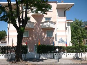 特伦托卡尼丰塔纳别墅酒店的前面有棵树的粉红色建筑