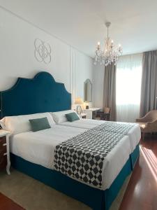 塞维利亚塞维利亚德比酒店的一间卧室配有一张大床和一个吊灯。
