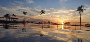 阿拉亚尔-杜卡布Apart-Hotel Golden Lake 2的棕榈树和日落的海水游泳池
