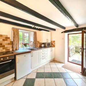 朗塞斯顿Ta Mill Cottages & Lodges - Pump Cottage的一间厨房,配有白色的橱柜和大窗户