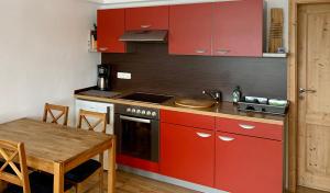 克林根塔尔Ferienwohnung Familie Becher Klingenthal Aschberg的厨房配有红色橱柜和木桌