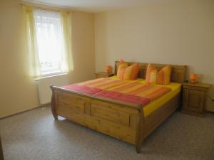 KirnitzschtalAm Lindenbaum的一间卧室配有一张带橙色枕头的大型木制床。