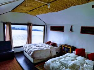 普诺Titicaca wasy lodge的一间卧室设有两张床和大窗户