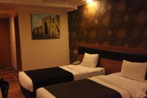 埃尔比勒埃尔比勒美尔奇酒店的酒店客房设有两张床,墙上挂有绘画作品