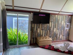 曼谷Kurina Hotel的卧室设有大窗户和平面电视。