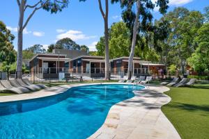 阿德莱德Levi Adelaide Holiday Park的一座树木繁茂的房屋前的游泳池