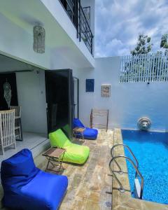 NgingasBreezes Villa的游泳池旁设有蓝色和绿色的椅子