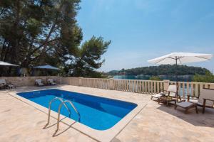 普利兹巴Apartment Prižba - Korčula的一个带椅子和遮阳伞的游泳池