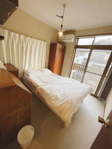 镰仓市Children's cafe B&B Kimie的卧室配有白色的床和窗户。
