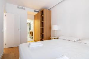 马德里3 bedrooms 2 bathrooms furnished - Salamanca - Stylish - MintyStay的卧室配有白色的床和衣柜。