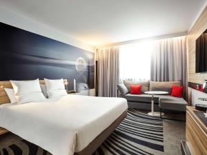 比肯希尔诺富特伯明翰机场酒店的酒店客房设有一张大床和一张沙发。