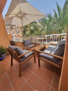 莫哈卡尔Marina Golf Mojacar Playa的庭院配有两把椅子和一把遮阳伞