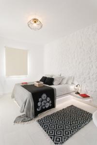 米科利维亚Naxos Earth Suites的一间白色卧室,配有一张床和黑白地毯