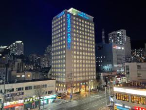 釜山釜山西面托优克酒店的一座高大的建筑,上面有蓝色的灯光