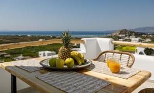 米科利维亚Naxos Earth Suites的桌上的水果盘,加上一杯橙汁
