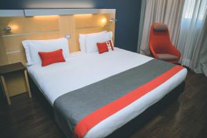 卡萨诺韦米兰马尔彭萨快捷假日酒店的一间卧室配有一张大床和一张红色椅子