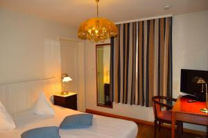 迪斯特Oranje City Hotel的一间卧室配有一张床、一张书桌和一个吊灯。