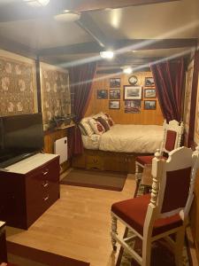 普里茅斯Rare 1954 Renovated Vintage Lorry - Costal Location的一间卧室配有一张床、一台电视和椅子