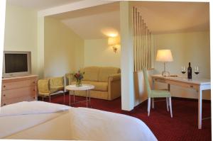 Neukirchen an der Vöckla本布克哈泽旅馆酒店的酒店客房配有一张床、一张沙发和一张书桌。