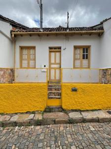 欧鲁普雷图Cantinho em Ouro Preto的黄色和白色的房子,有黄色的门