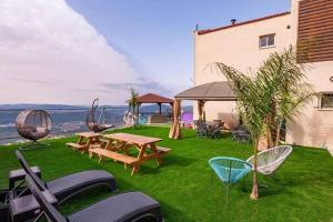 ‘Ein el AsadBlue lake luxury villa for families的后院在草地上设有野餐桌和椅子