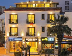 切什梅Horasan Boutique Hotel的一座白色的大建筑,设有窗户和棕榈树