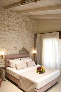 罗希姆诺Philikon Luxury Suites的一间卧室配有一张带鲜花的大床