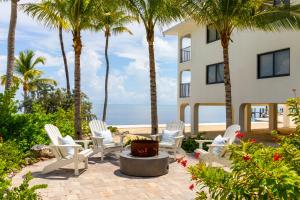 伊斯拉莫拉达La Siesta Resort & Villas的一个带白色椅子和棕榈树的庭院以及大海