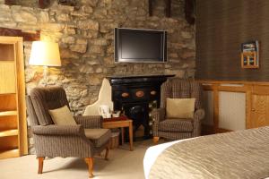 柯比朗斯代尔太阳旅馆的一间卧室设有壁炉、两把椅子和一张床
