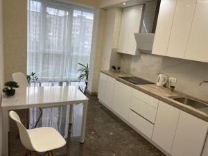 罗夫诺2 кімнатні ,Люкс апартаменти в ЖК Арена ,район автовокзалу的厨房配有白色橱柜、水槽和桌子