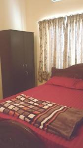 门格洛尔Christa Homestay, AC,near A.J. Hospital, Mangalore的一间卧室配有一张带红色床单的床和橱柜。