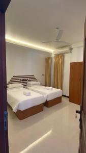 古莉Beach Walk Villa Maldives的一间卧室设有两张床和天花板